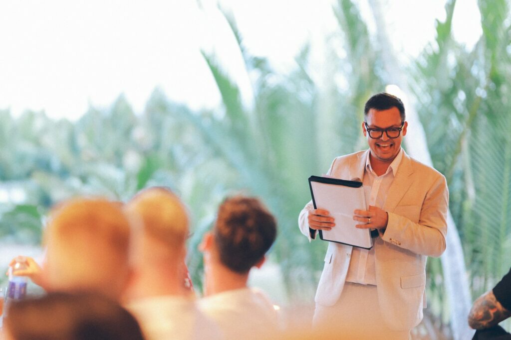 Man in suit holding clipboard speaking to audience